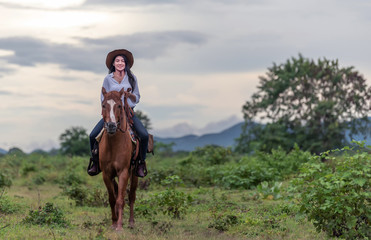 cowgirl  riding on a mountain with an yellow sky; Concept of friendly  and of summer vacation.