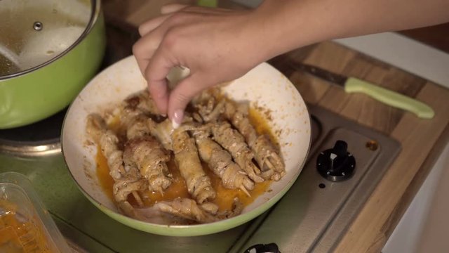 Female cook frying skewers With Chunks of Meat in pan on stove