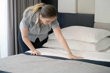 Maid making bed in hotel room. Housekeeper Making Bed