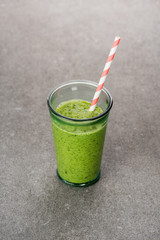 Blended green and healthy smoothie in glass with straw