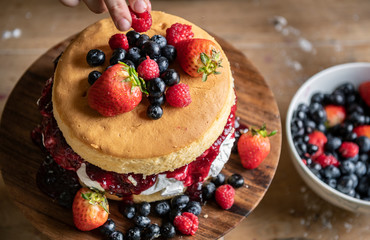Woman decorating a layered cake with berries