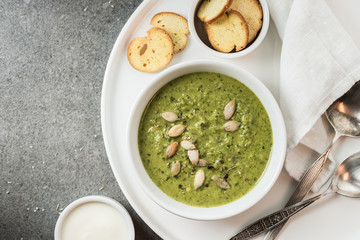 Top view of green vegetable creamy soup in bowl on tray