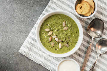 Top view of homemade green creamy soup with croutons and sour cream