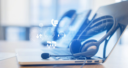 close up soft focus on headset with telephone devices at office desk for customer service support with communication icon technology concept	