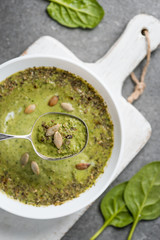 Close up of silver spoon with green vegetable creamy soup in bowl