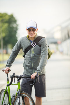 Image of young sporty man in sunglasses standing next to bicycle