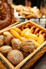Assortment of freshly baked breads, dinner rolls and pretzels in a wooden box for appetizer or meal starter. Looks tasty and delicious. Good source of carbohydrate. Not gluten-free. Selective Focus.