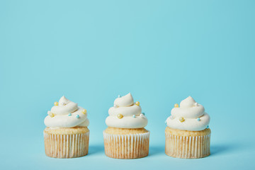 Tasty cupcakes with sugar sprinkles on blue background