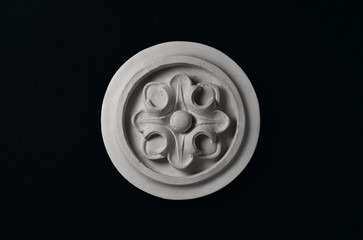 White stucco flower in a circle on a black background.