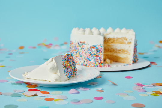 Piece of cake with cut cake on blue background with confetti