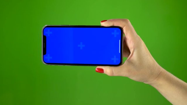 Phone in female hand on green screen