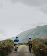 Obraz premium Couple cycling down a road in the Scottish Highlands