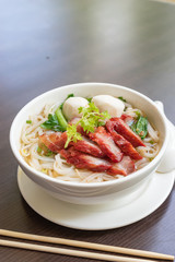 BBQ pork noodle bowl on a wooden table