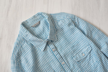 Blue striped shirt on wooden background. Fashionable concept. Clouse up