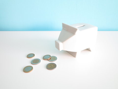 White ceramic piggy bank with euro coins on the table 