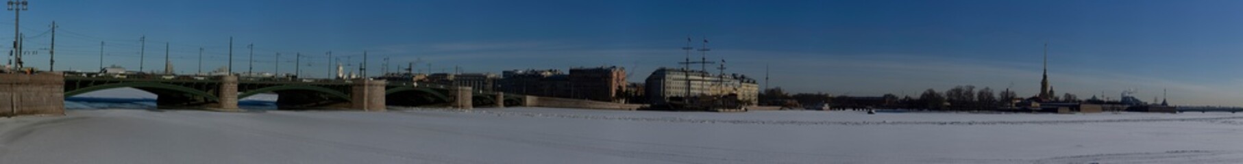 Fototapeta na wymiar Winter panorama of St. Petersburg overlooking the Exchange bridge and Peter and Paul Cathedral. On the frozen Neva river patrol hovercraft Emercom.