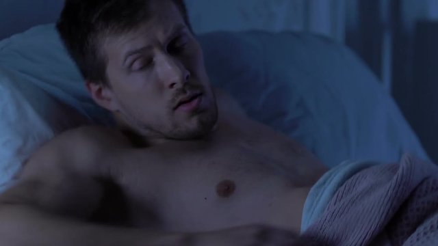 Man awakened by disturbing dream, suffering from nightmares, sleep disorder