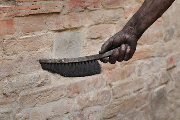 Closeup of chimney sweeper hand holding brush dirty of char