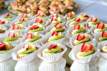 Close up of small sweet canapes arranged on a mirror plate over light background - selective focus