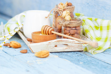 Almonds, honey and jar with milk on the wooden tray