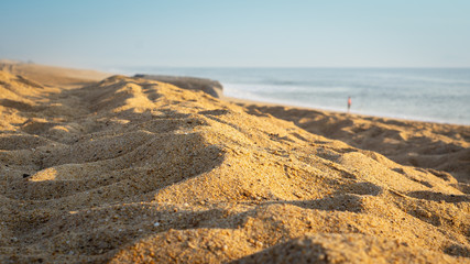 Arena de playa con un hombre al fondo en verano