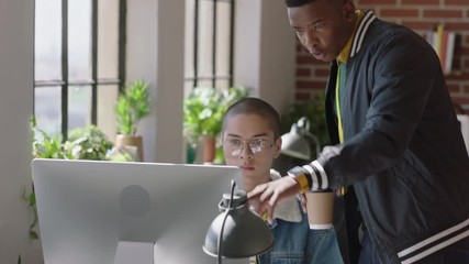 young mixed race man using computer helpful african american team leader sharing ideas pointing at screen training colleague discussing project solution in diverse office