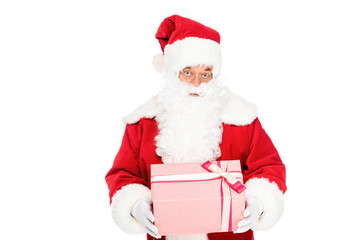 expressive santa claus holding gift box and looking at camera isolated on white