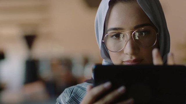 muslim business woman in cafe using tablet computer working online browsing social media sharing lifestyle enjoying relaxing reading messages wearing hijab headscarf