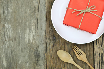 Red Gift Box in white dish on wooden floor and have wooden spoon.