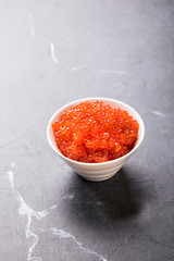 Salmon  Red Caviar in a white plate on a dark background. Healthy Food Concept. Snack.Copy space for Text.Seafood.