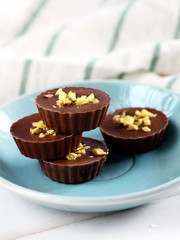 Milk chocolate cup candys with pistachio on the blue plate