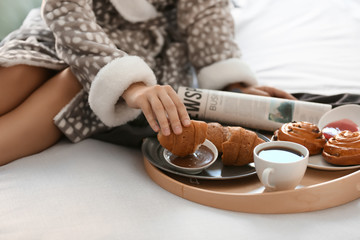 Fototapeta na wymiar Young woman having delicious breakfast on bed