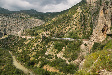 Fototapeta na wymiar Train crossing a tunnel in a large valley in ardales, andalucia, surrounded by hills and a river