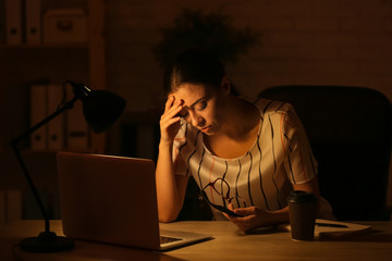 Woman suffering from headache while working at home late in evening
