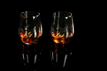 Glasses of whiskey on black background