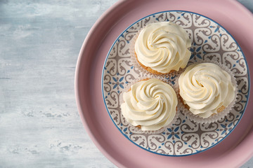 Plate with delicious cupcakes on grey table