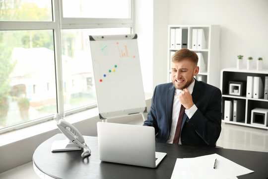 Emotional young businessman after making mistake while working with laptop in office
