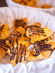 Assortment of delicious and buttery croissants drizzled with chocolate icing made by pastry chef. All look very tasty and delightful. Natural light.