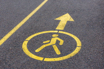 yellow sign on asphalt. footpath with directional arrow