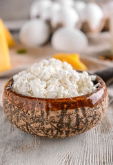 Bowl with delicious cottage cheese on wooden table
