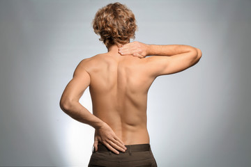 Obraz premium Young man suffering from back pain on light background