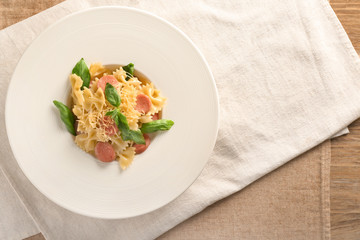 Plate with delicious macaroni and cut sausage on table