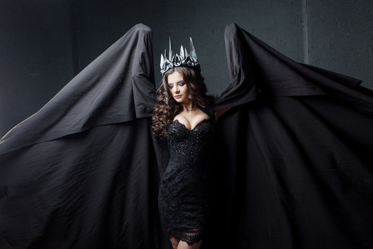 Portrait of a Gothic Princess. Beautiful young brunette woman in metal crown and black cloak.