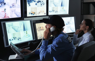 Security guards monitoring modern CCTV cameras in surveillance room