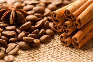 Obraz na płótnie Canvas Coffee beans, anise and cinnamon on brown burlap. Close up