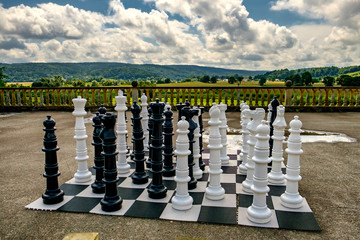 Big Chess pieces on a board in an open-air park. 