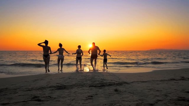 Group of family friends running in Slow Motion together on a beach at sunset, cinematic shot, SLOW MOTION