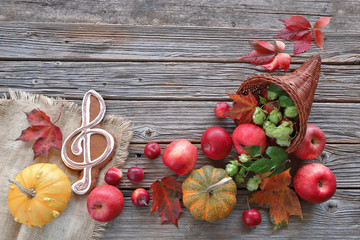 Cornucopia with apples, autumn leaves, pumpkins , music gingerbread on wooden background 