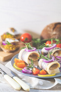 Delicious rolled herring fillet with red onion, cherry tomatoes, lemon and rosemary