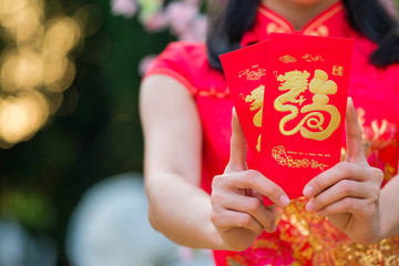 The girl in the red dress of Chinese descent is happy with the red envelope with the dollar.